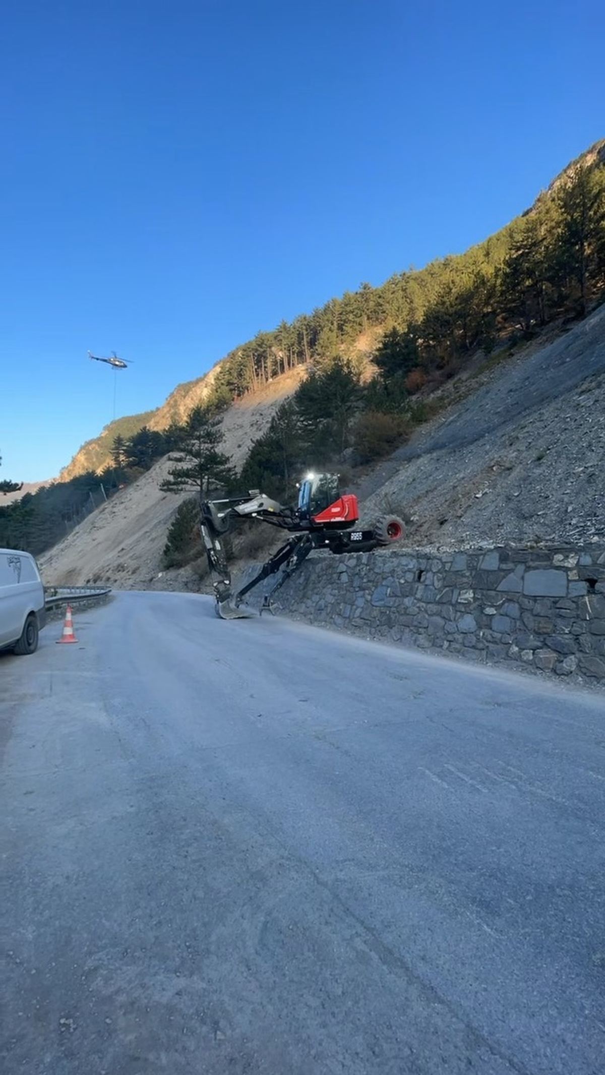 Pelle araignée Acropelle R955 en intervention, hélicoptère en arrière-plan